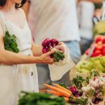 Hands putting fruits and vegetables in a cotton produce bag at food market. 