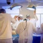 Masked surgeons perform surgery.