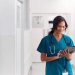Female doctor in scrubs in hospital using a digital tablet.