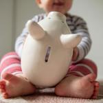 Young baby playing with a piggy bank.