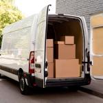 White van with its back doors open, showing the back full of cardboard boxes.