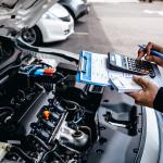 Mechanic calculates the cost of car repairs to customer at garage workshop.