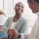 Man and woman shaking hands while sitting.