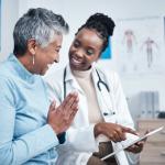 Doctor and elderly patient viewing news on a tablet.