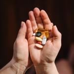 Hands hold supplements on blurred background.
