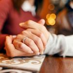 Close up of couple's hands holding in cafe. 
