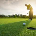 Golfer putting golf ball on the green.