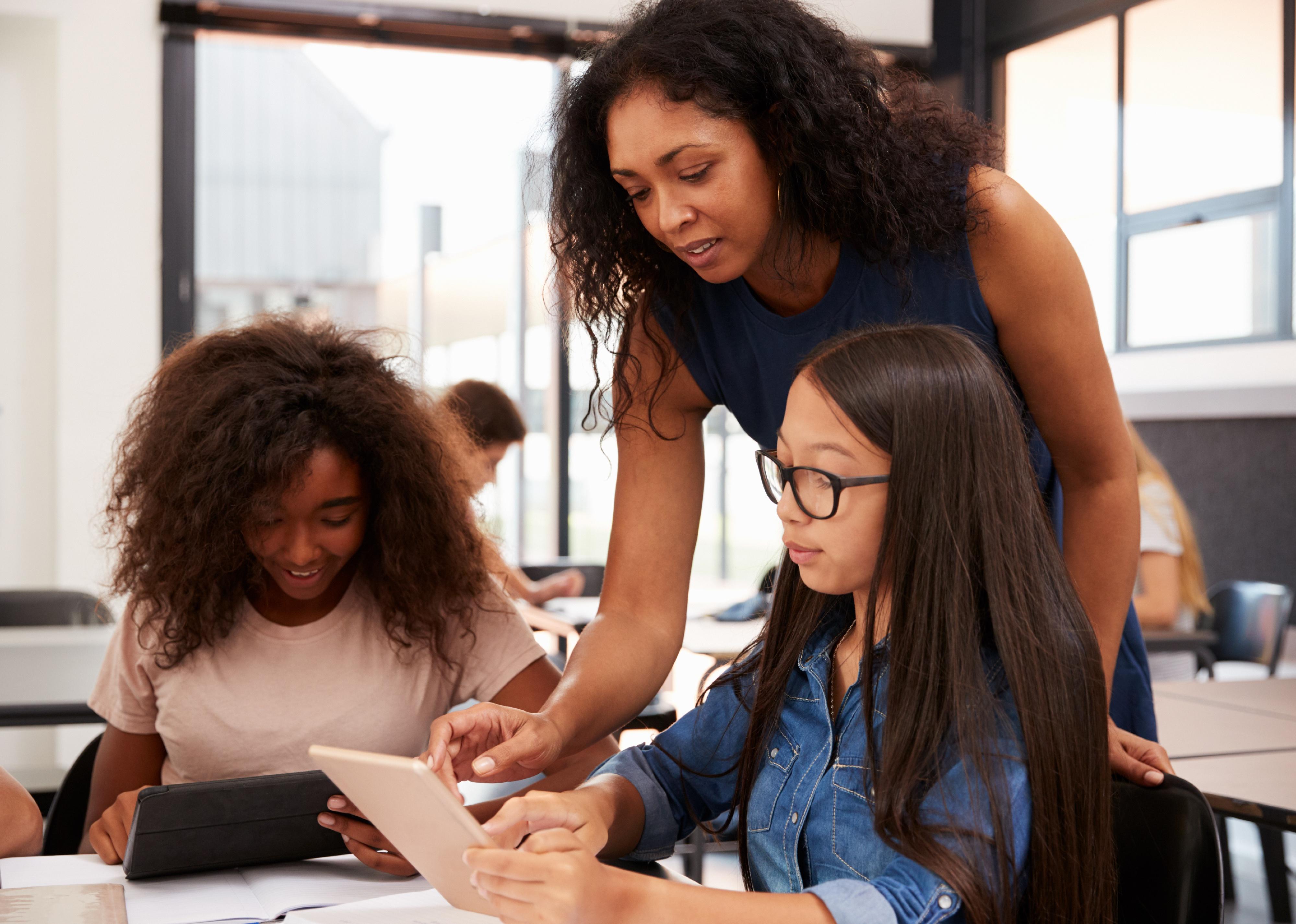 Teacher helping high school students with technology