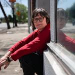 Julie Crossman sitting on a stoop wearing a red long-sleeve shirt, is the sister of Nanie Crossman who she lost touch with, in Oakland on April 8, 2025