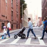 Two families crossing a road along an apartment neighborhood.
