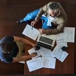 Two businessmen discussing strategy with accounting documents on their table.