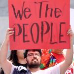 Demonstrators hold signs during the We The People March in Los Angeles, California.