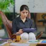 Young businesswoman in workplace using a tablet to browse information online.