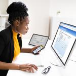 Woman using a phone and computer to use online banking.