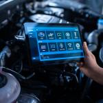 A mechanic using a tablet to configure a car's issue and repair.