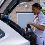 A travel nurse putting her bag in the trunk of her car.