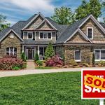 Home with green lawn and "For sale" sign covered by the word "sold."