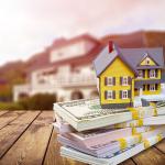 A figure of a house on top of bundles of cash.