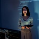 A learning & development employee standing in front of a screen where software lessons are projected.