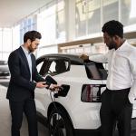 A dealer selling a white electric SUV to businessman in a car dealership.