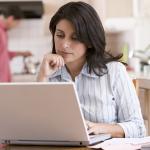 Woman using a laptop at her home's kitchen.