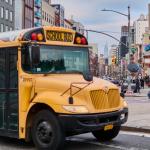 A yellow school bus passing a street in New York City.