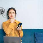 A young woman trying to think of an idea while holding her phone.