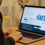 A student browsing the FAFSA website on a laptop.