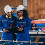 A pair of industrial workers inspect their factory's machines.