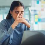 A frustrated young woman in front of her laptop at work.