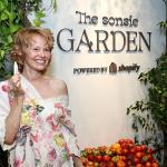 Pamela Anderson poses holding up a lip produce in front of "Sonsie Garden" with Shopify on October 24, 2025 in New York City.