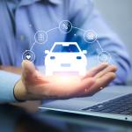 A car insurance agent using a laptop with graphics of car insurance concepts illustrated over his hand.
