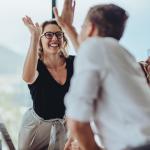 A businesswoman getting a high-five from a colleague.