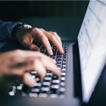 Hands typing on laptop