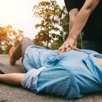 A person performing CPR on a man having a heart attack