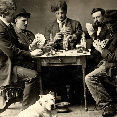 A black and white 1909 photo of five men playing poker around a table.
