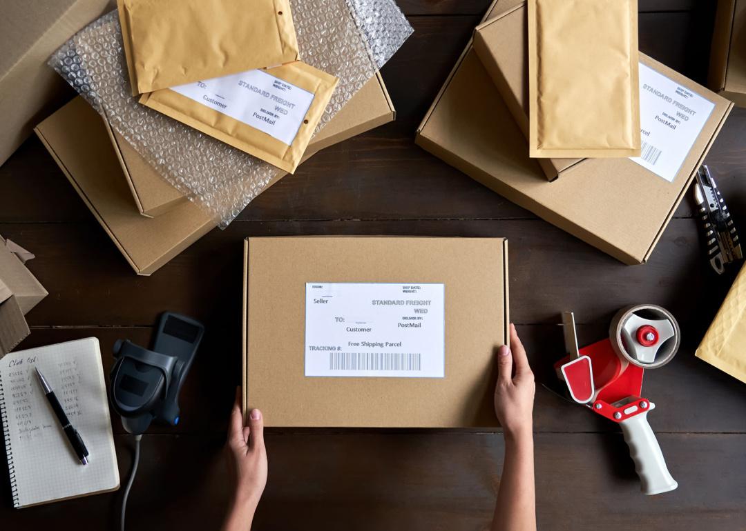 Hands of warehouse worker or packing ecommerce box for dispatching
