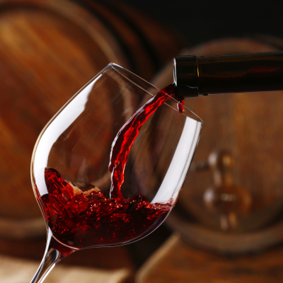 Close up pouring wine with casks in background