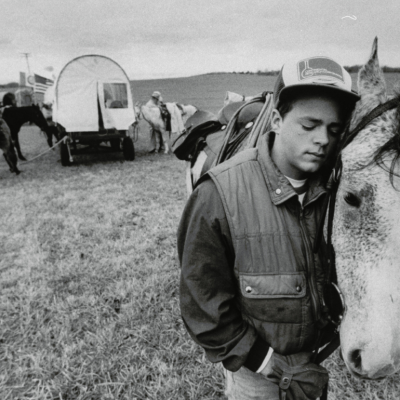 Young man nuzzling up to his horse in open field while reenacting the Trail of Tears journey in 1988.