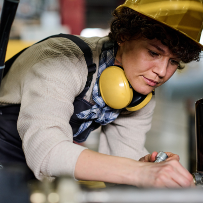 Worker in protective gear assembling industrial equipment
