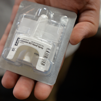 Hand holding Narcan nasal spray package.