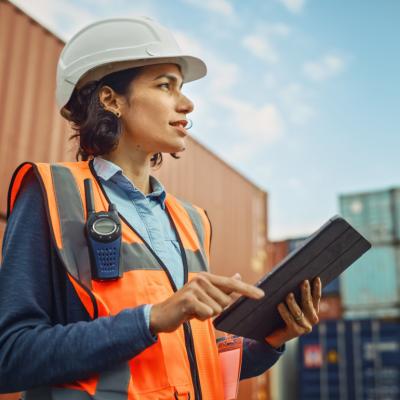 Supervisor in shipping container terminal holding tablet.