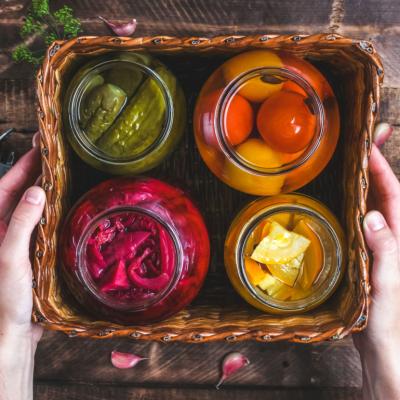 Glass jars of homemade pickled vegetables in box.
