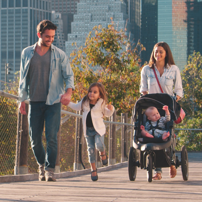 Family with stroller and city skyline in the background.
