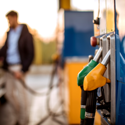 A man pumping gas with green and yellow gas pumps in the foreground