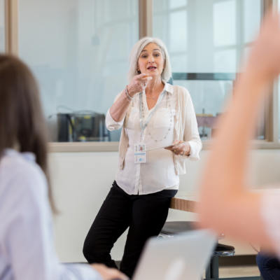 An female teacher addresses two students in a classroom