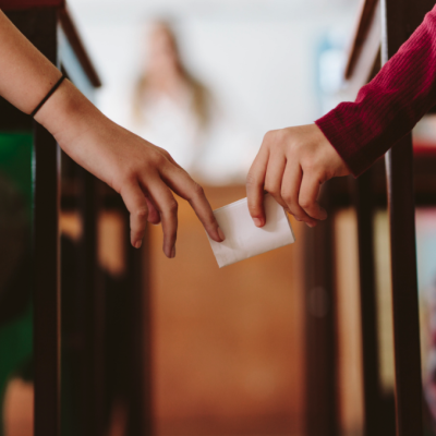 Hands of two students passing a note in class