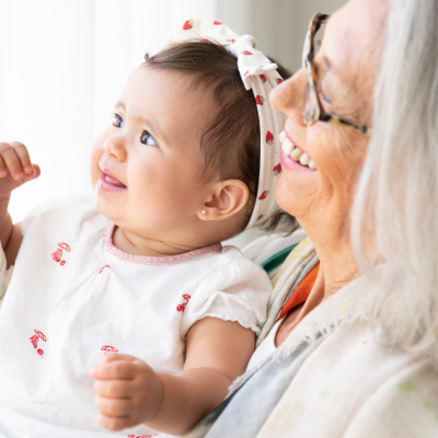 Grandmother holds granddaughter while smiling.