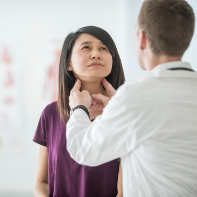 Doctor examining woman's thyroid, checking for cancer.