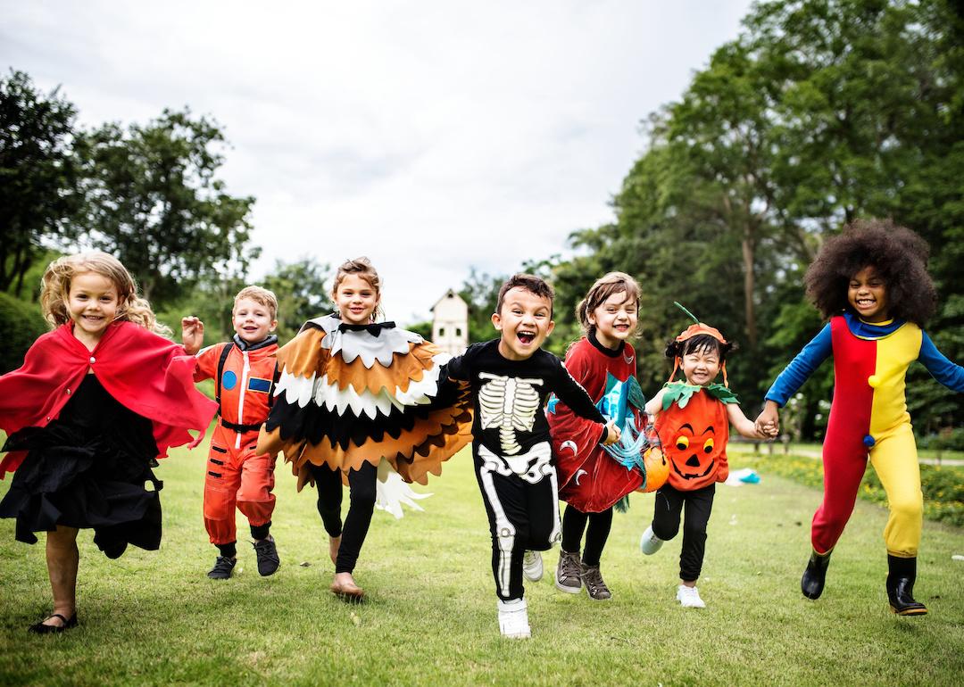 Little kids running through the grass dressed up at a Halloween party